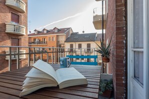 Un banc en bois sur lequel repose un livre ouvert et une tasse, une plante en pot et, au fond, un autre banc bleu.