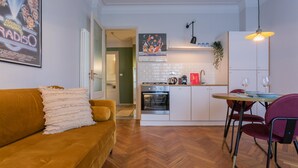 A compact kitchen with white cabinets, a built-in oven, and a dining area with a table and chairs. - Casa Paradiso by Wonderful Italy (Turin)