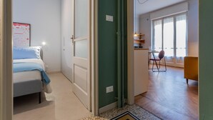A bedroom with a bed, a desk, and a chair in a bright room with large windows. - Casa Paradiso by Wonderful Italy (Turin)