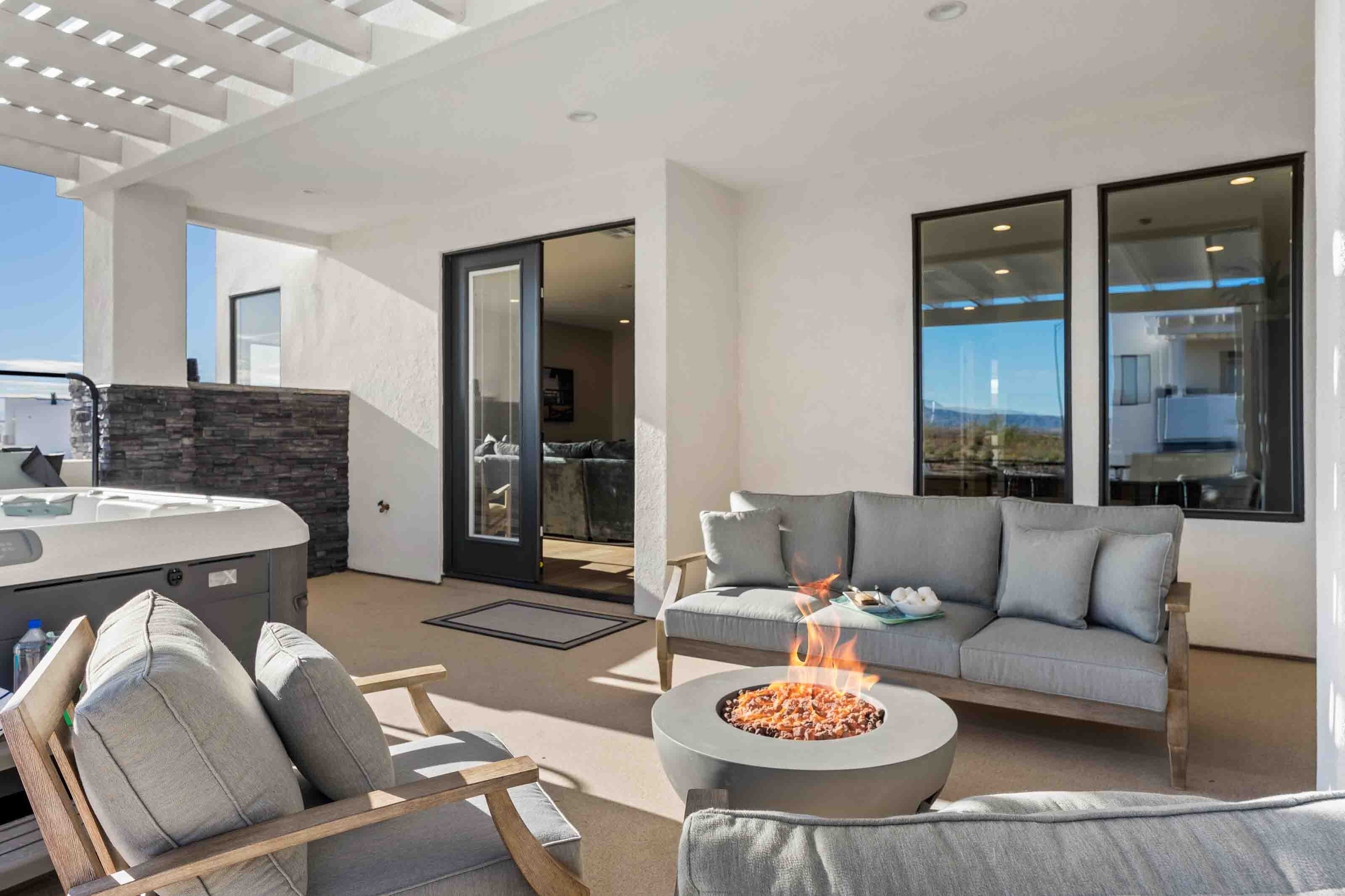 A modern outdoor living area with a fire pit, a sofa, and a hot tub.