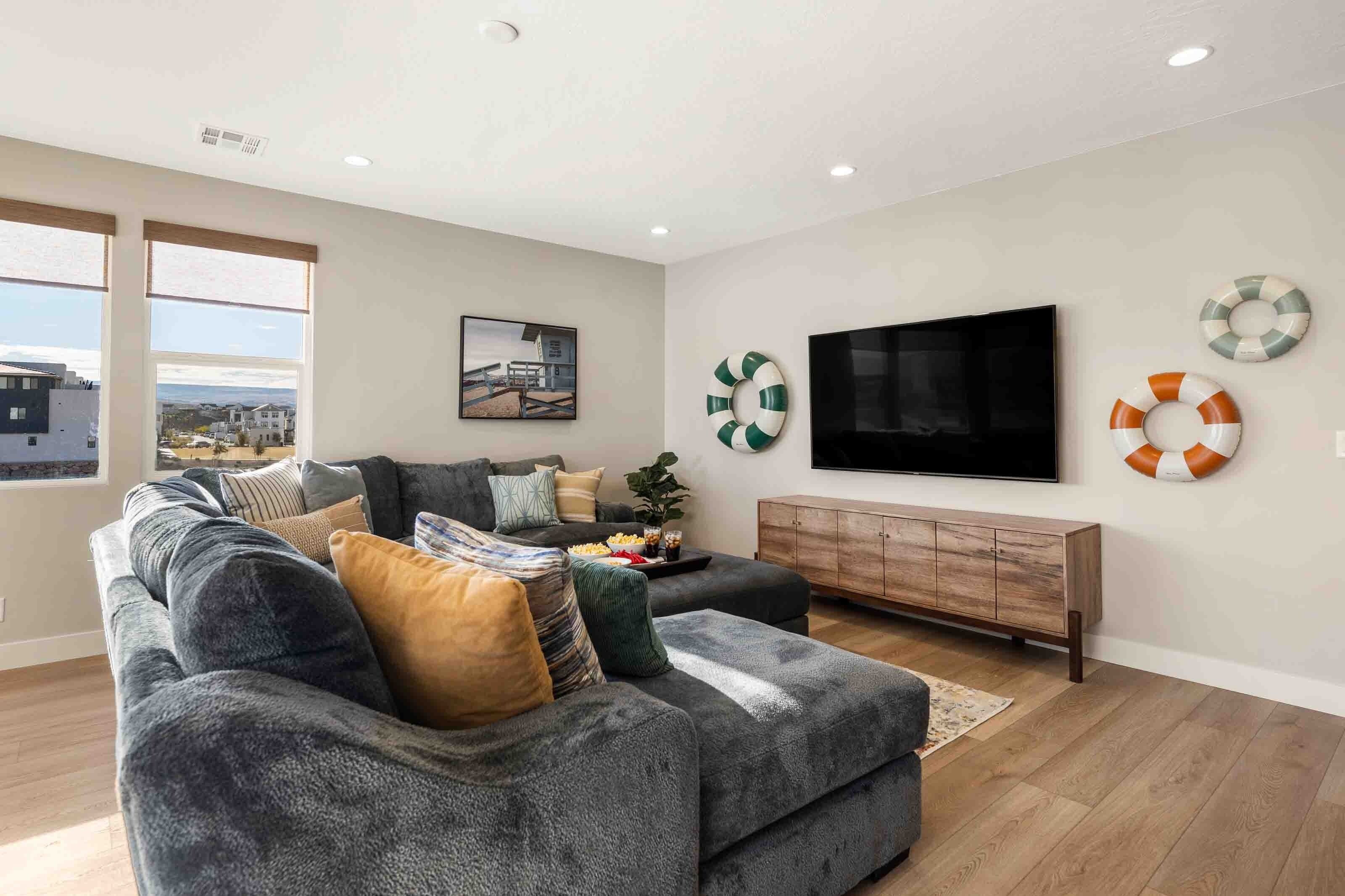 A modern living room with a grey sectional sofa, a flat-screen TV, and a wooden cabinet.