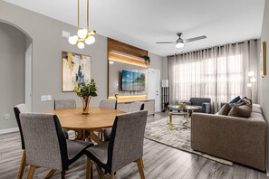 A modern living room with a dining area, a sofa, and a TV. - 2306 SP - Disney Villa 2BR Pool Near Magic (Kissimmee)