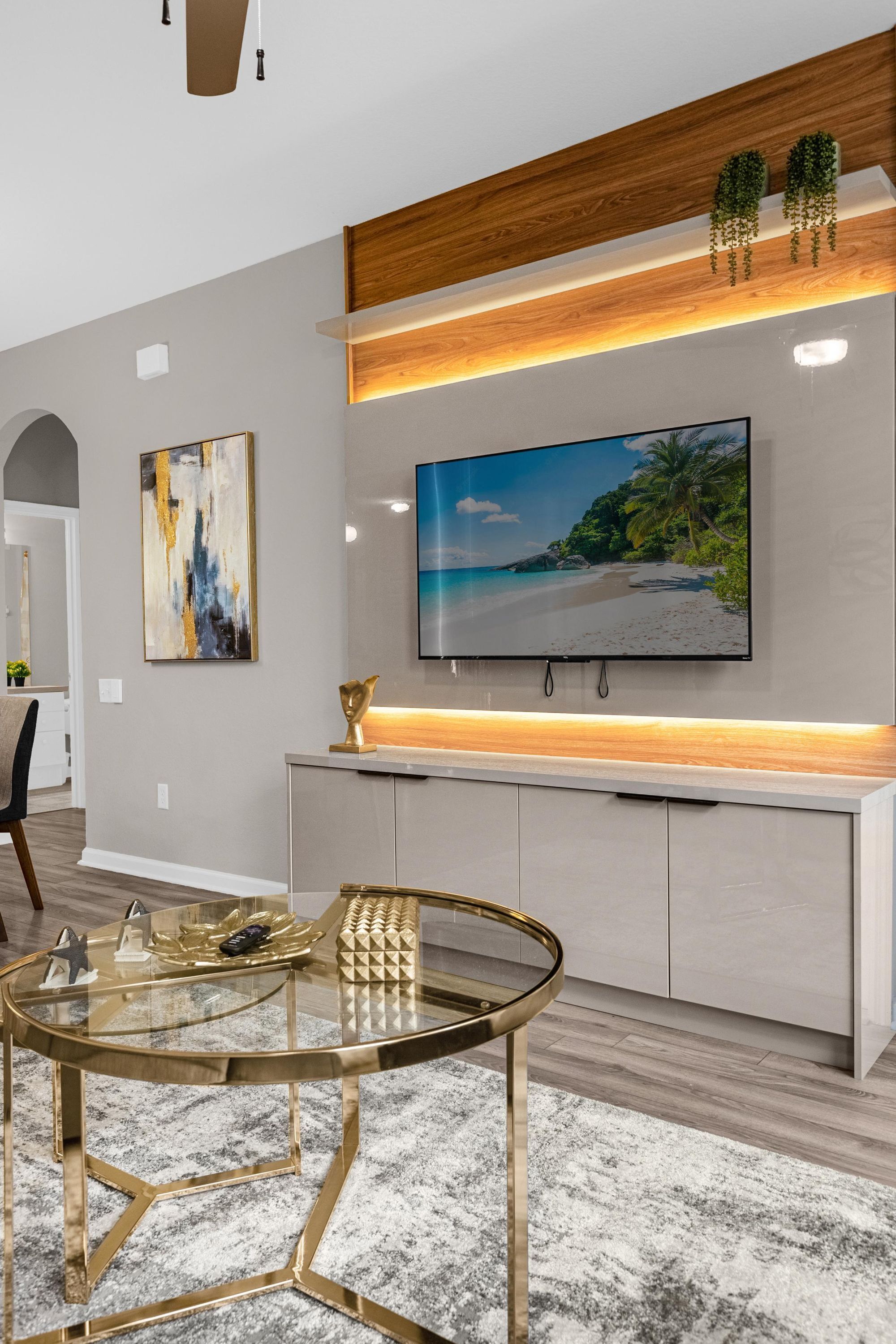 A modern kitchen with a built-in TV, a glass coffee table, and a wooden ceiling.