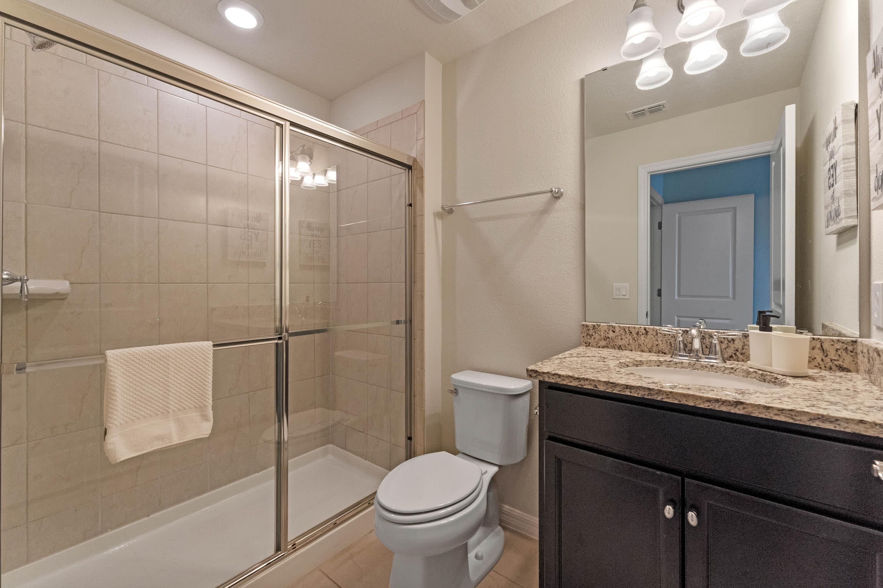 A bathroom with a glass-enclosed shower, a toilet, and a vanity with a sink.