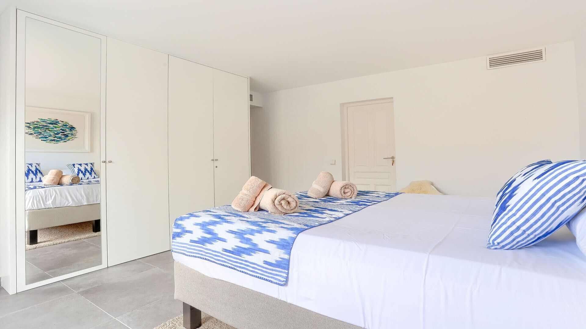 A bedroom with a bed, a wardrobe, and a bathroom visible through an open door.