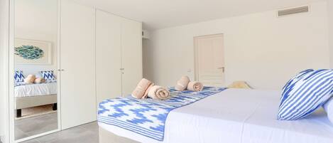 A bedroom with a bed, a wardrobe, and a bathroom visible through an open door.