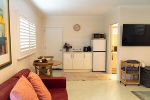 Ett kompakt bostadsutrymme med ett litet kök, en matplats och en sittgrupp med en röd soffa.