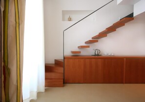 Una cocina moderna con encimera de madera, estufa integrada y una escalera con escalones de madera.