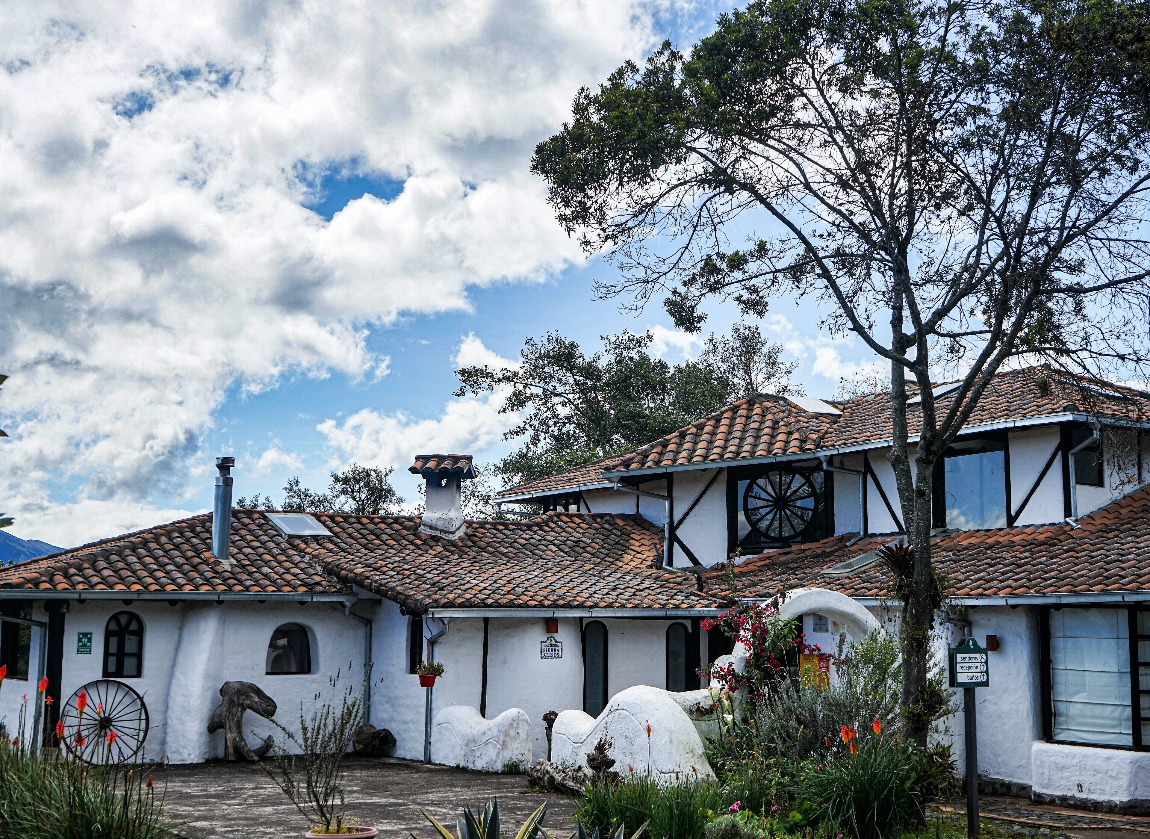 A traditional building with a tiled roof, white walls, and a large wheel structure.