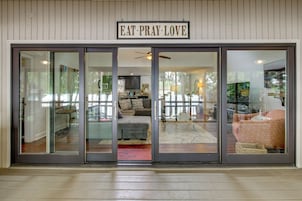 A modern entrance with a glass door, a ceiling fan, and a sign that reads 'EAT PRAY LOVE'.
