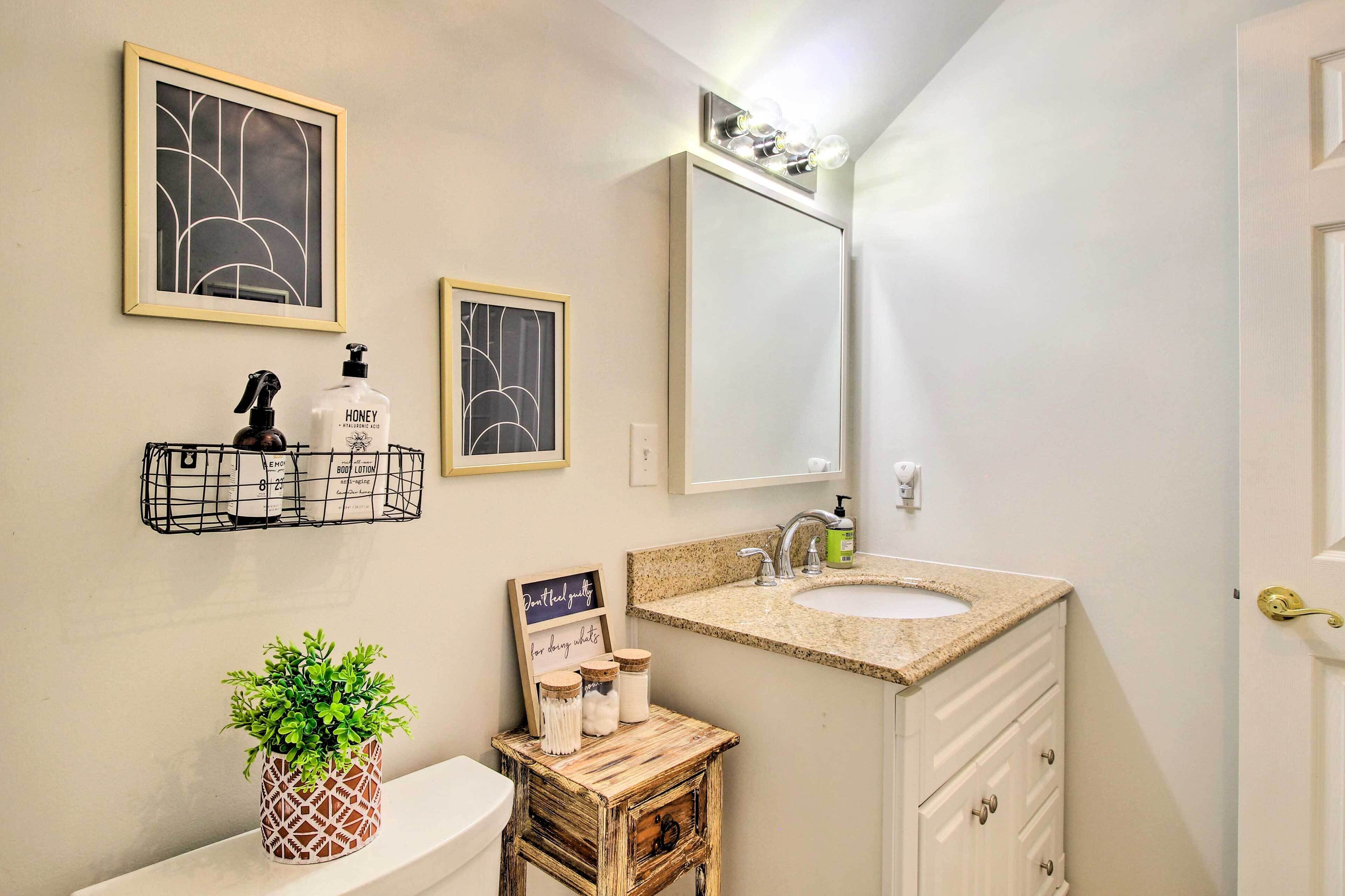 A bathroom with a white sink, a mirror, and a framed abstract artwork above the mirror.