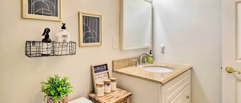 A bathroom with a white sink, a mirror, and a framed abstract artwork above the mirror.