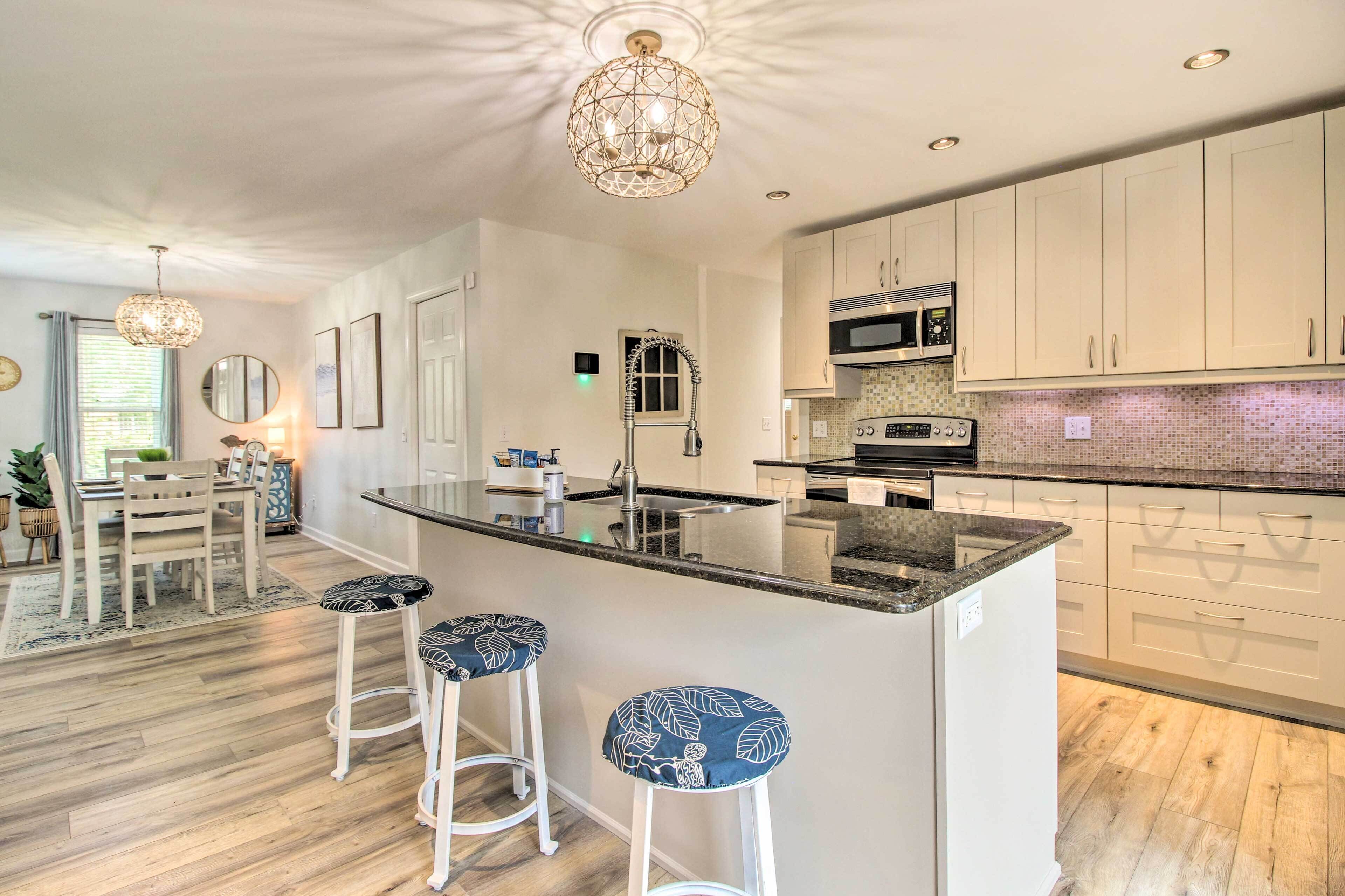 A modern kitchen with a central island, bar stools, and a dining area with a table and chairs.