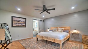 Une chambre à coucher avec un lit, un ventilateur de plafond, un tapis et une étagère fixée au mur.