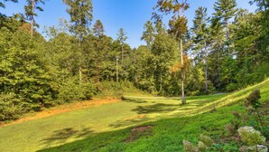 Un paisaje verde y exuberante con un campo de golf, rodeado de árboles frondosos y un cielo despejado.