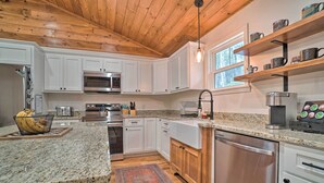 A modern kitchen with granite countertops, stainless steel appliances, white cabinetry, and a wooden ceiling. - Painted Skies Upscale Getaway By Lake Burton! (Tiger)