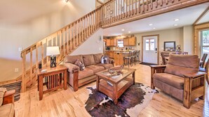 A spacious living area with a wooden staircase, a sofa, a coffee table, and a cowhide rug. - Stunning Blue Ridge Retreat w/ River Access! (Blue Ridge)