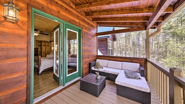 A wooden cabin with a porch featuring wicker furniture and a bed. - Stunning Blue Ridge Retreat w/ River Access! (Blue Ridge)