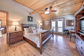 A bedroom with a wooden ceiling, a bed with a headboard, a dresser, a desk with a chair, and a television. - Stunning Blue Ridge Retreat w/ River Access! (Blue Ridge)