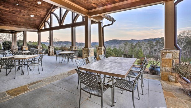 Un patio al aire libre con mesas y sillas, pilares de piedra y vistas del paisaje circundante.