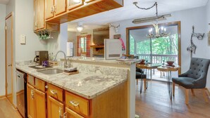 Una cocina con armarios de madera, encimera de granito y comedor con una silla y mesa.