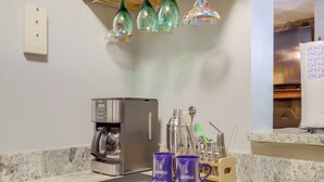 Una cocina con cafetera, dos tazas y un microondas.