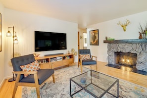 A modern living room with a flat-screen TV, comfortable seating, a stone fireplace, and a decorative wall. - Hot Tub, 5 Mi to Dtwn! Newly Updated Seattle Home (Seattle)