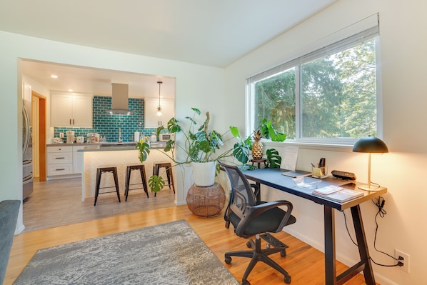 Een moderne keuken met witte kasten, een blauwgroene spatwand en een centraal eiland met krukken.