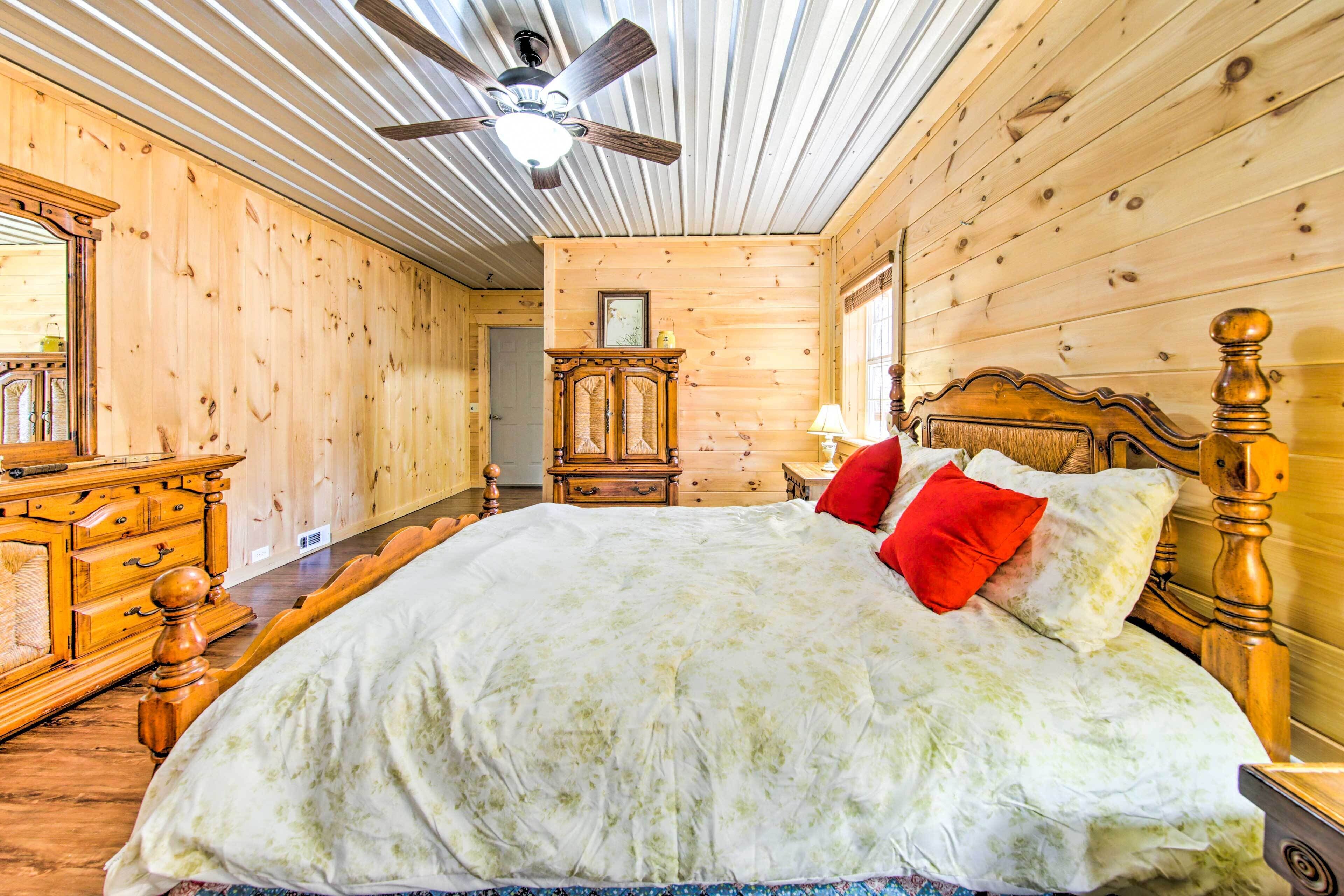 Una habitación con paneles de madera, una cama, un aparador, un espejo y un ventilador de techo.