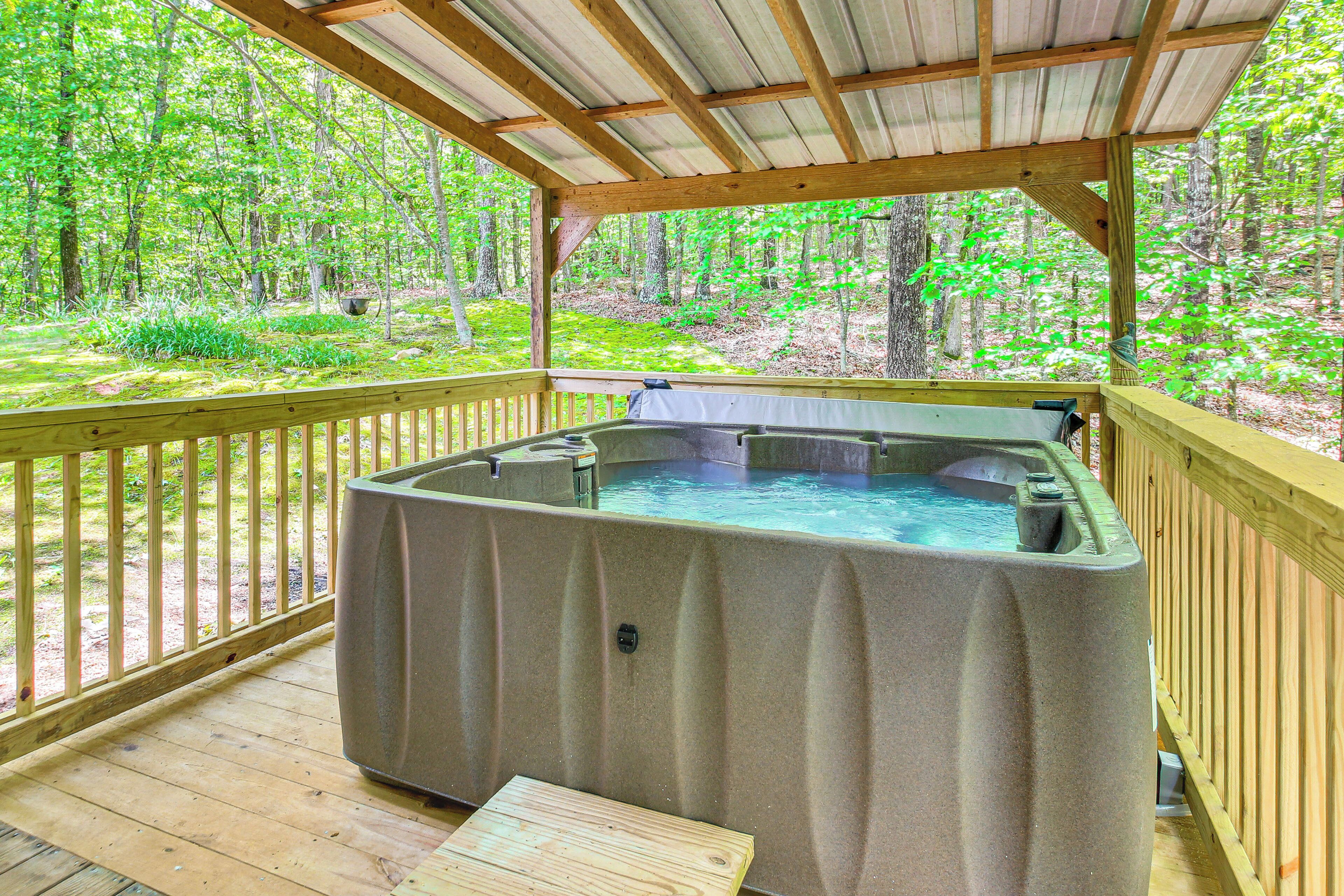 Un jacuzzi en una terraza de madera con vista a un bosque.