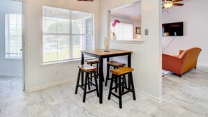 A dining area with a table and four stools, a ceiling fan, and a TV mounted on the wall. - Peaceful Savannah Home - 11 Mi to Beaches! (Savannah)