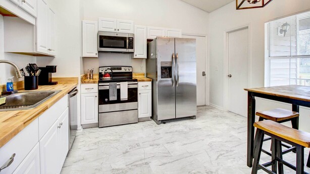 A kitchen with white cabinets, stainless steel appliances, a wooden countertop, and a bar stool. - Peaceful Savannah Home - 11 Mi to Beaches! (Savannah)