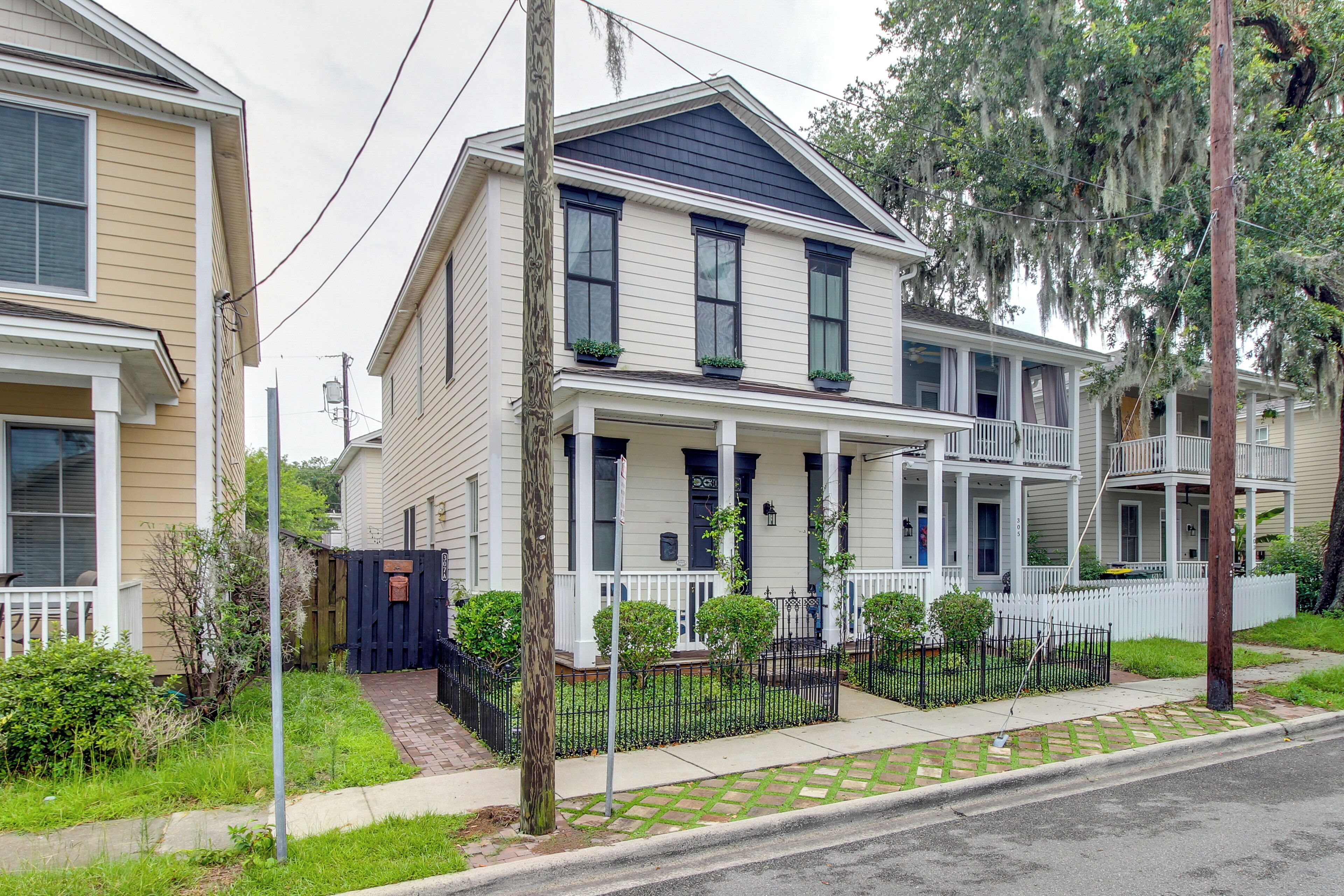A two-story house with a porch, a small front yard, and a black fence.