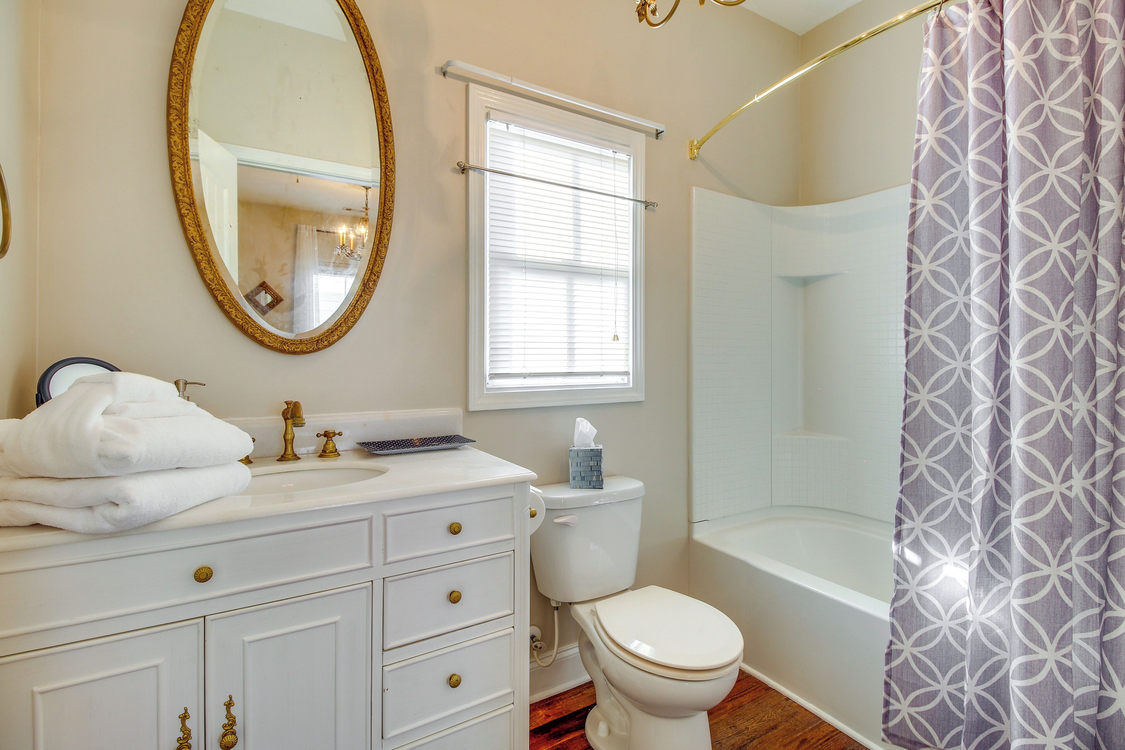 Une salle de bain avec un meuble-lavabo blanc, des toilettes, une baignoire et un rideau de douche.