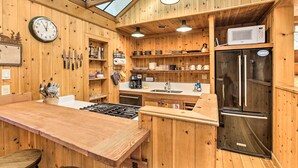 Un interior de madera con una zona de cocina que incluye estufa, refrigerador y microondas.
