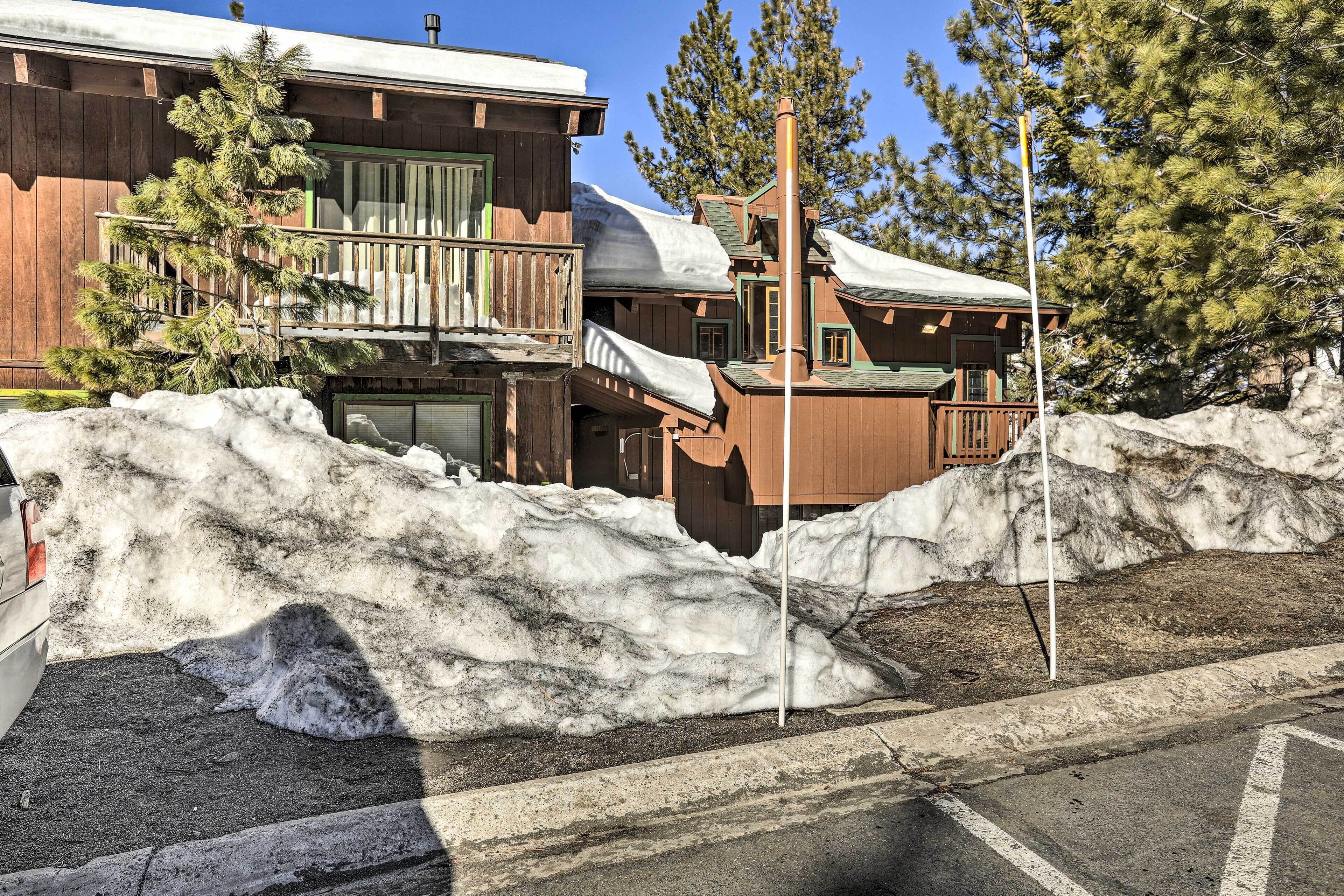 A wooden building with a balcony, surrounded by snow and trees.