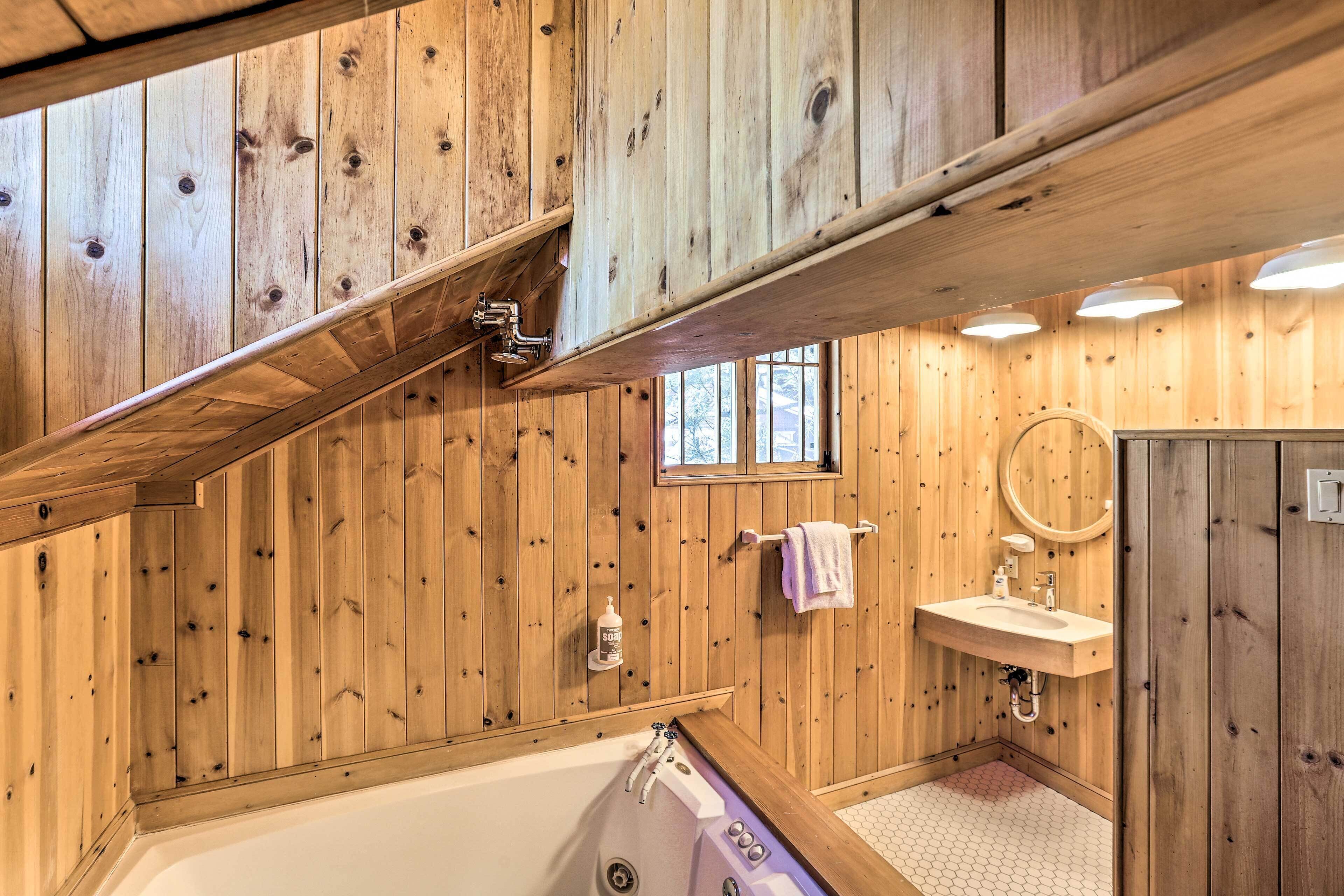 A wooden-paneled bathroom with a bathtub, sink, and window.