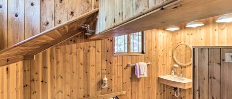 A wooden-paneled bathroom with a bathtub, sink, and window.