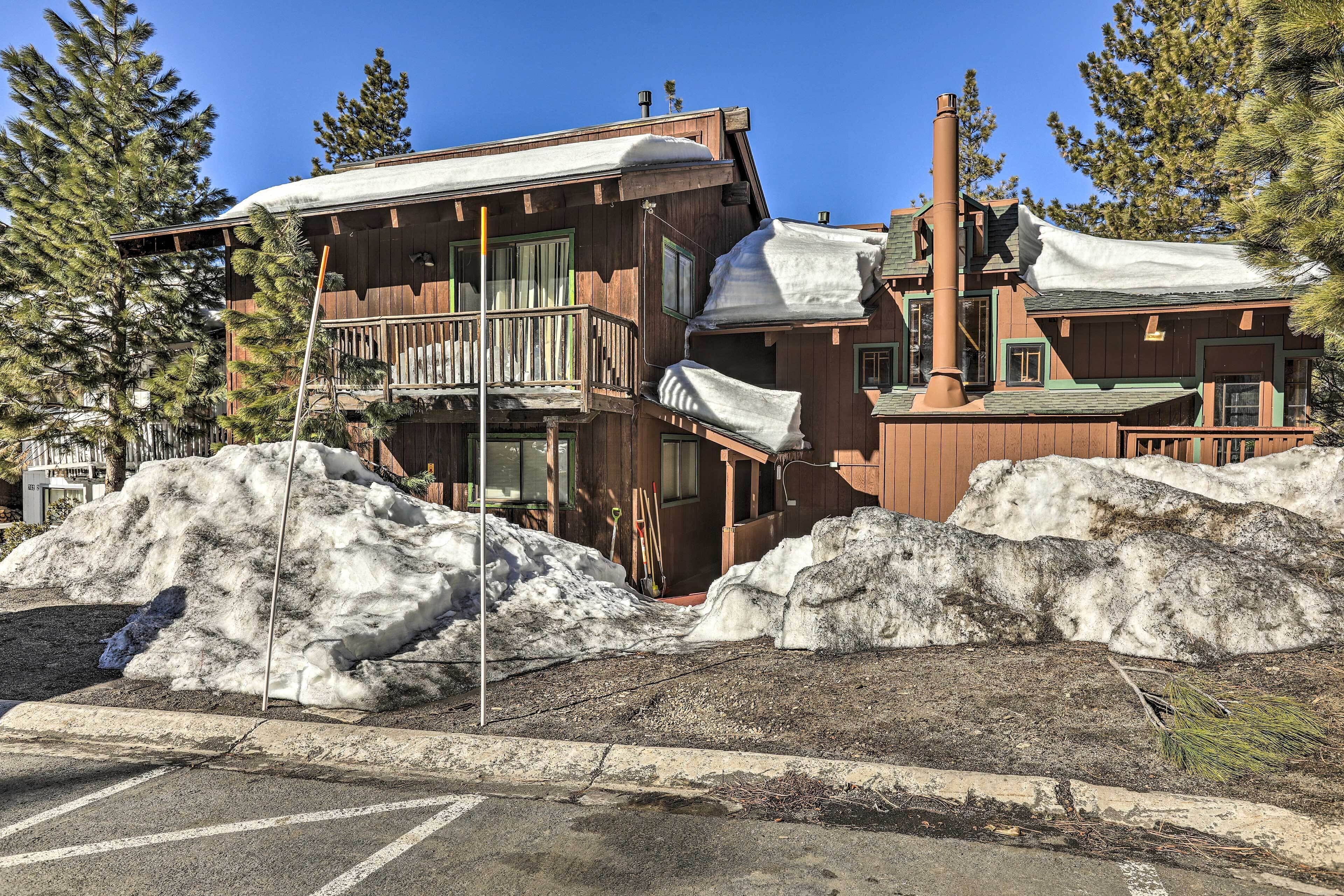 A wooden building with a balcony, surrounded by snow and trees.