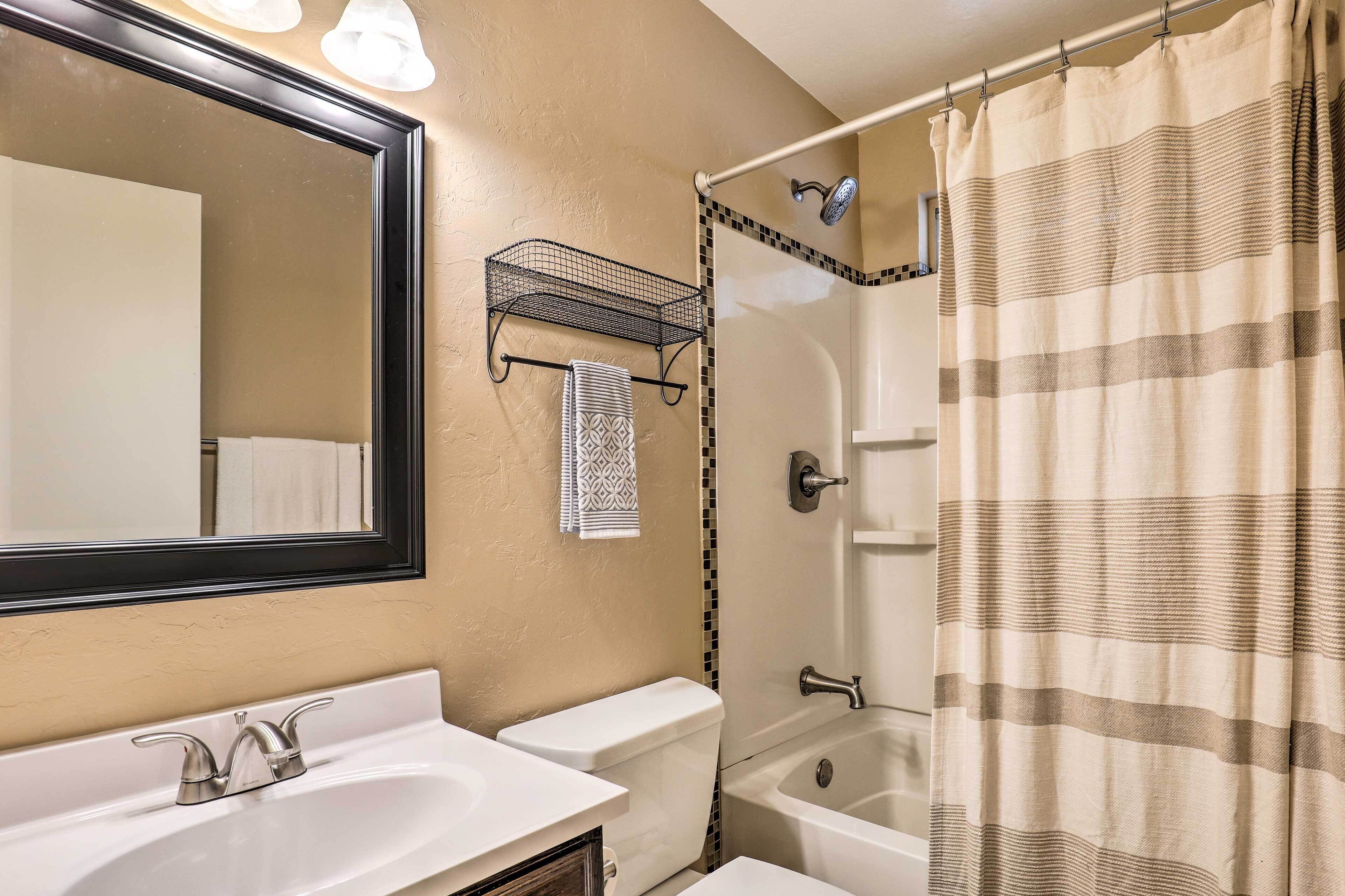 A bathroom with a sink, toilet, and bathtub, a shower curtain, and a towel rack.