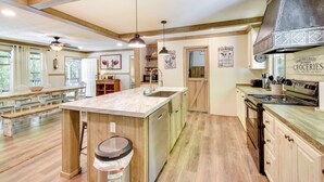 A spacious kitchen with wooden beams, a large island, and a built-in stove.