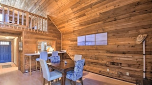 Un interior de madera con comedor, una escalera y vistas al exterior.
