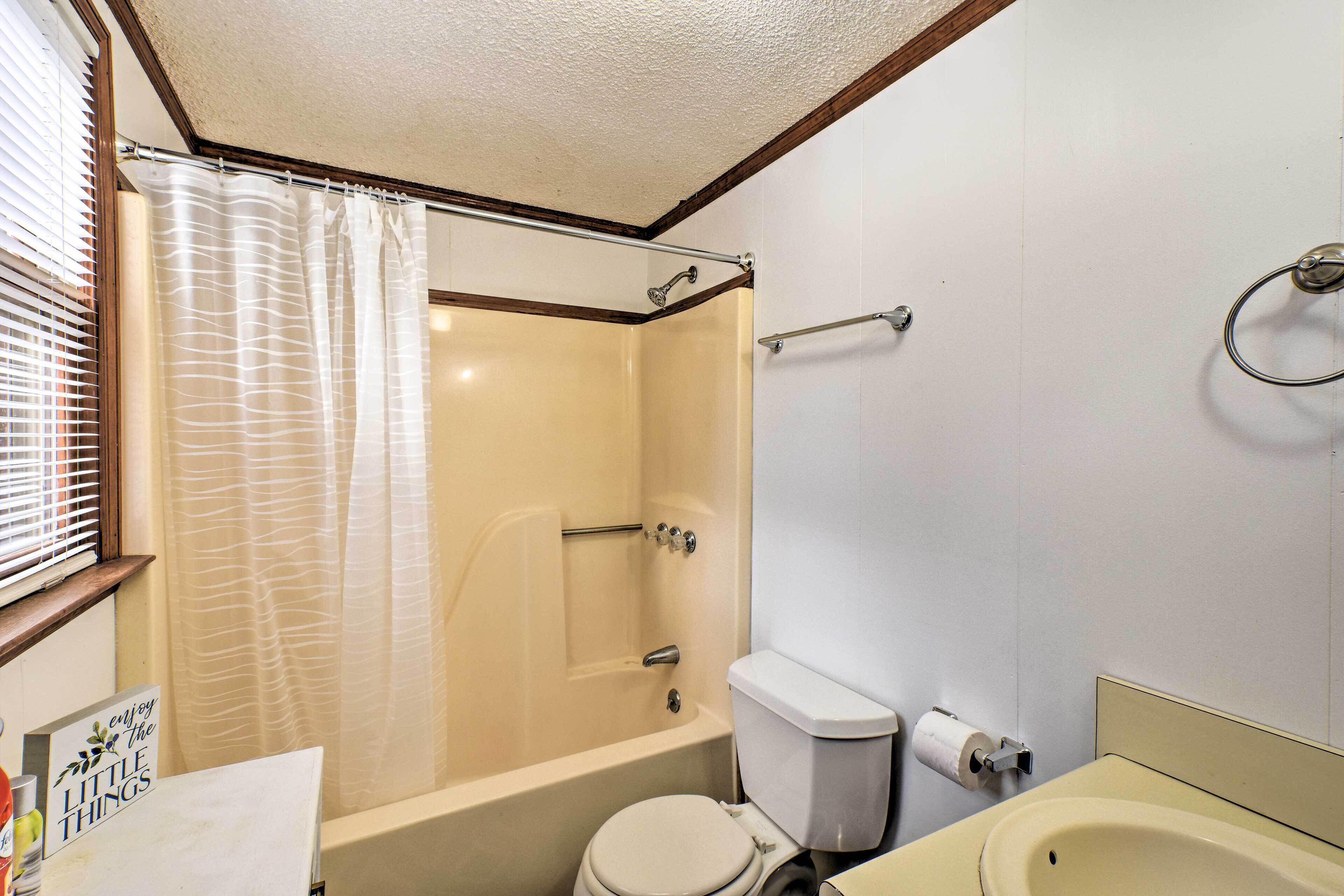 A bathroom with a shower, toilet, sink, and a towel rack.