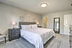 A bedroom with a bed, bedside tables, a chair, and a door. - Deck + Yard: Family-friendly Lawrenceville Home! (Lawrenceville)