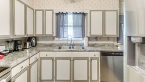 A kitchen with white cabinets, a stainless steel dishwasher, and a granite countertop. - Cozy Waycross House w/ Yard & Screened Patio! (Waycross)