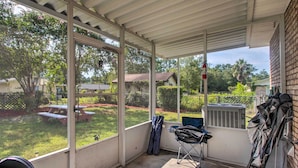 A covered patio with large windows, a folding chair, and an air conditioning unit. - Cozy Waycross House w/ Yard & Screened Patio! (Waycross)
