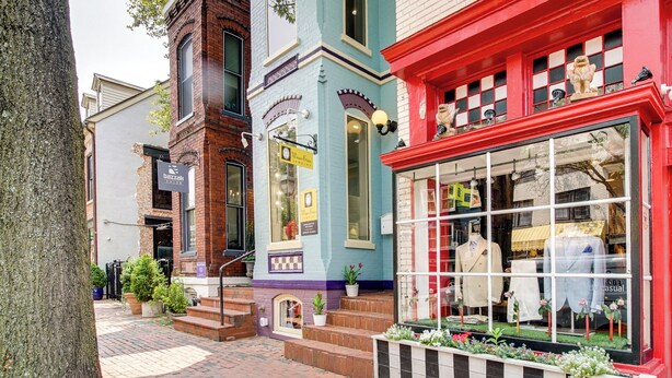 A street with colorful buildings, including a boutique with mannequins in the window.