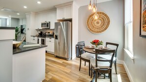 A modern kitchen with white cabinets, stainless steel appliances, and a dining area with a round table and chairs.