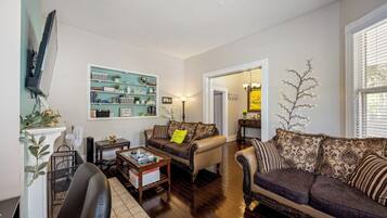 A living room with a sofa, a coffee table, a TV, and a bookshelf.