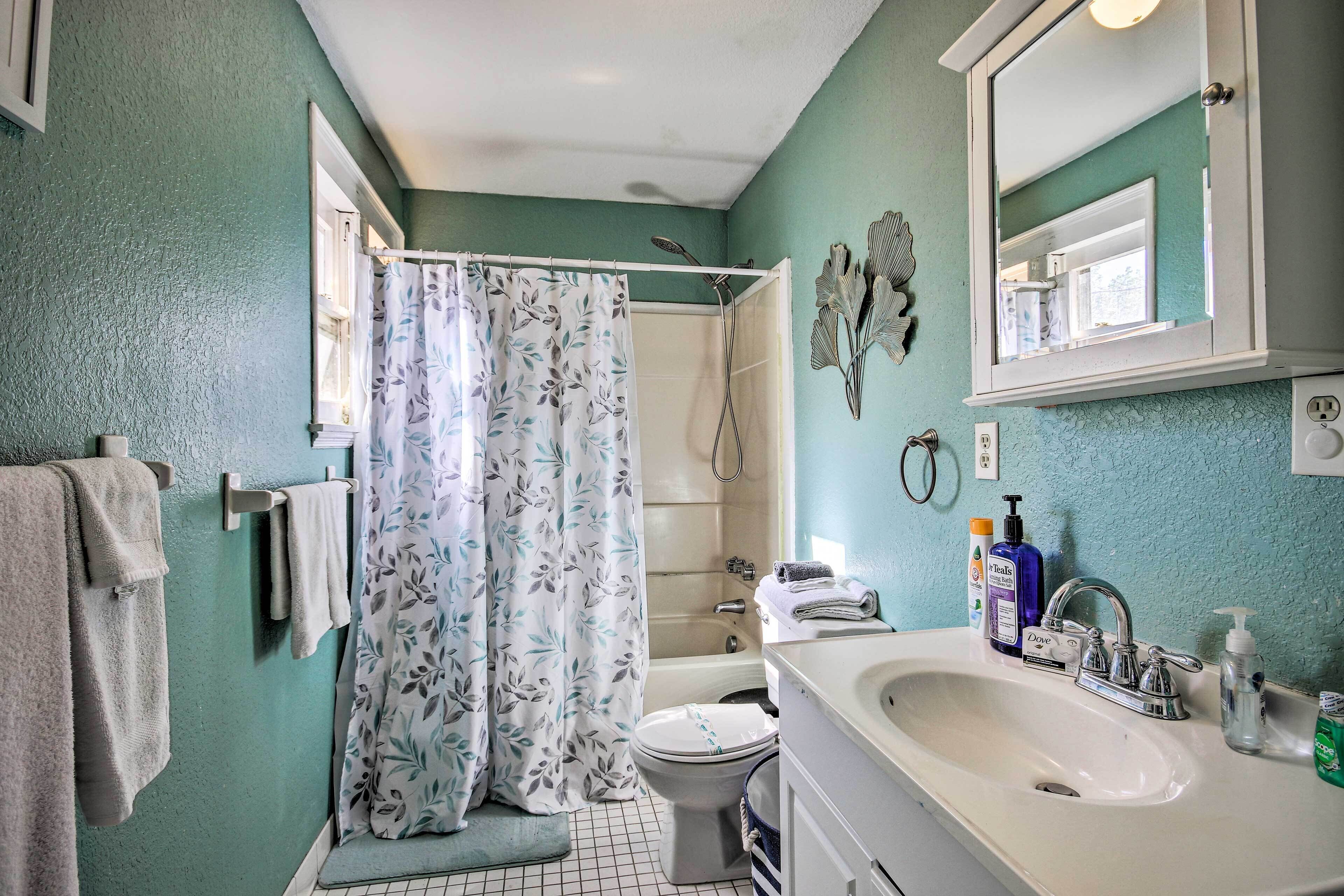 Un baño con ducha, inodoro, lavabo y espejo.